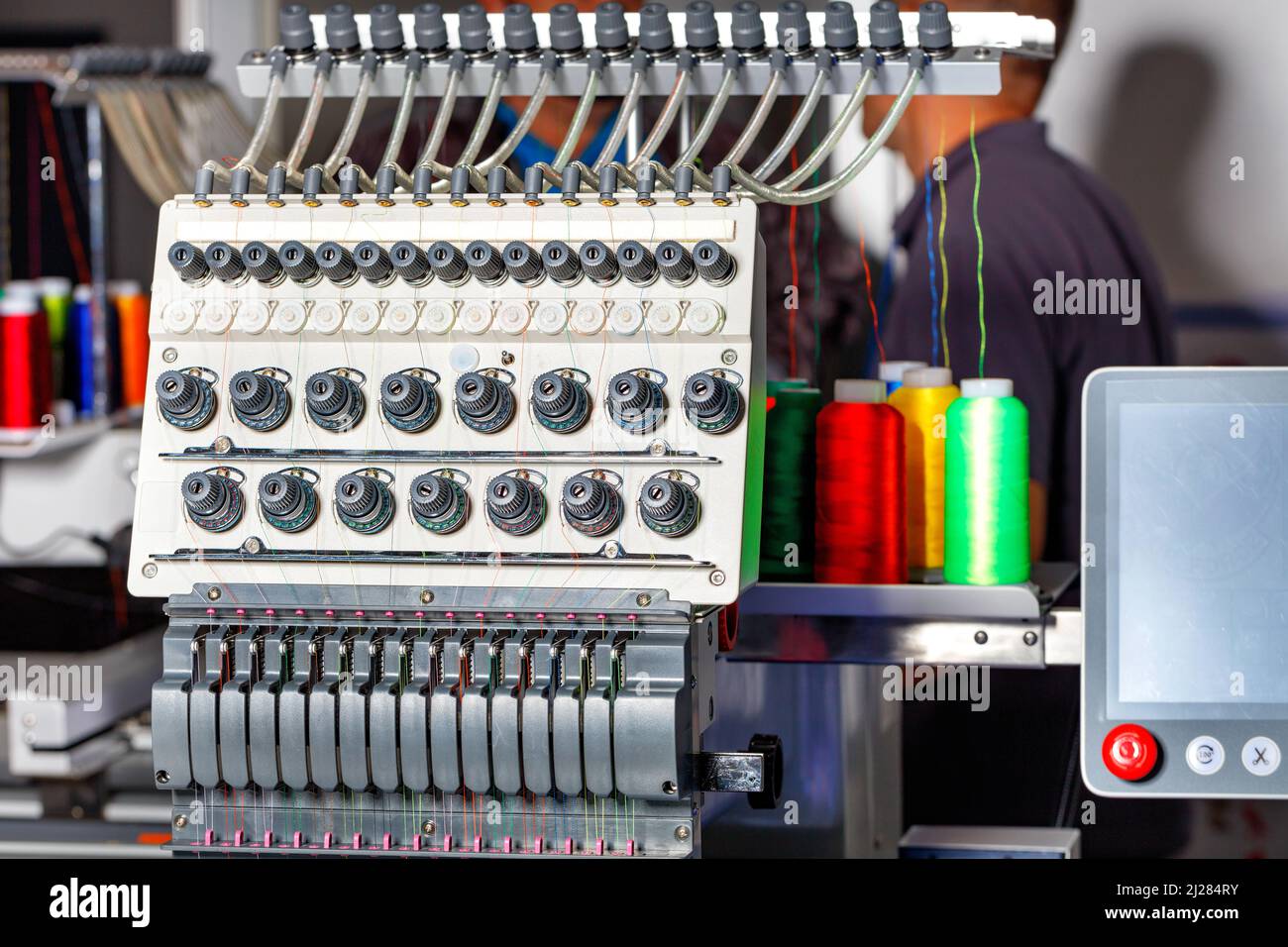 Modern electronic professional embroidery machine using preset programs for embroidery with multi-colored threads. Selective focus. Copy space. Stock Photo