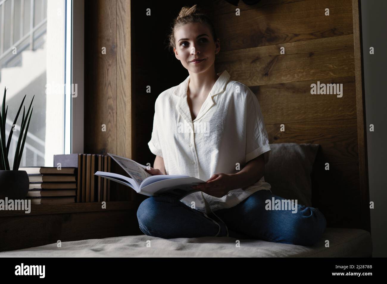 Portrait of young woman with book indoors at home, reading Stock Photo ...