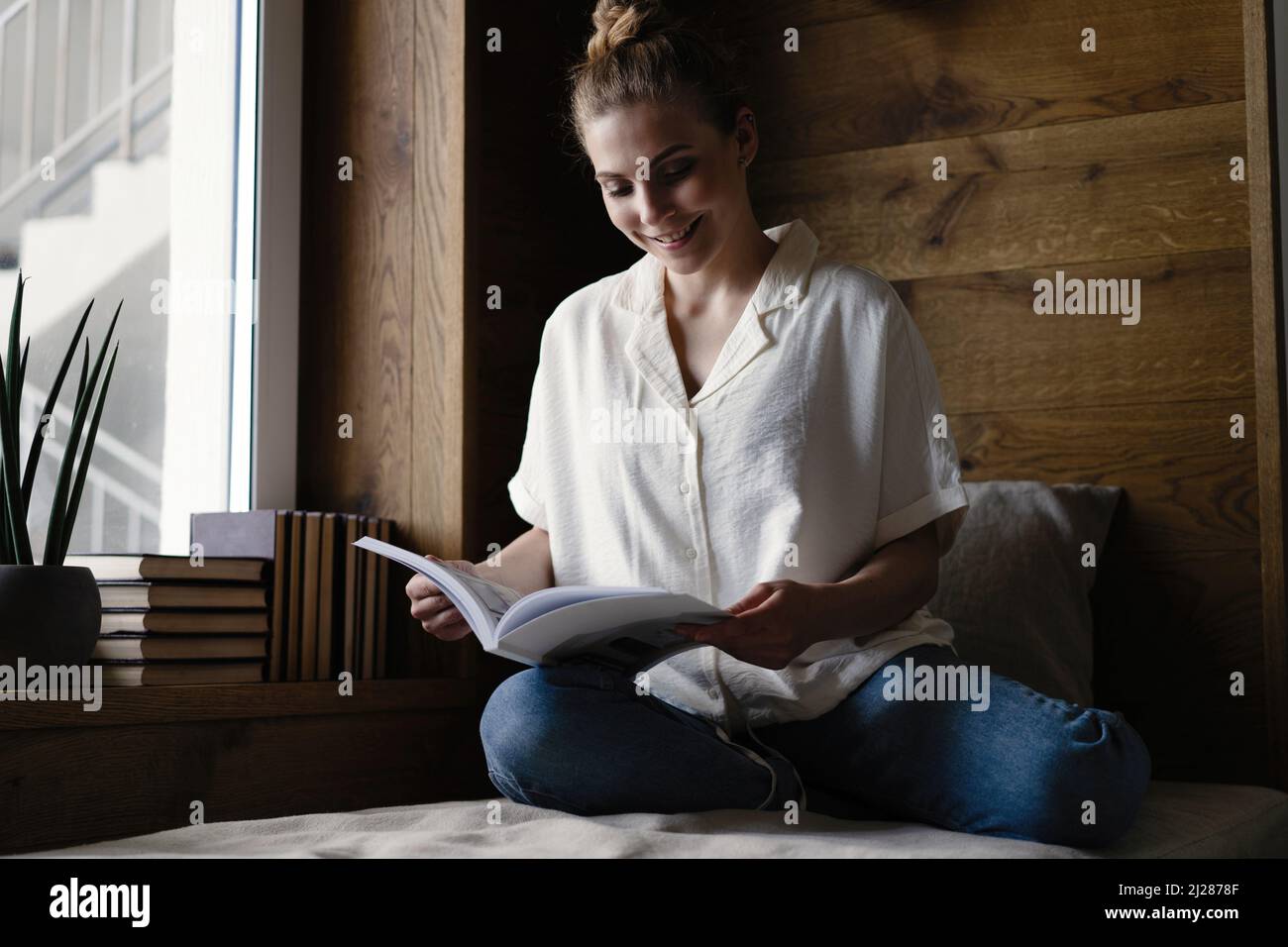 Portrait of young woman with book indoors at home, reading Stock Photo ...