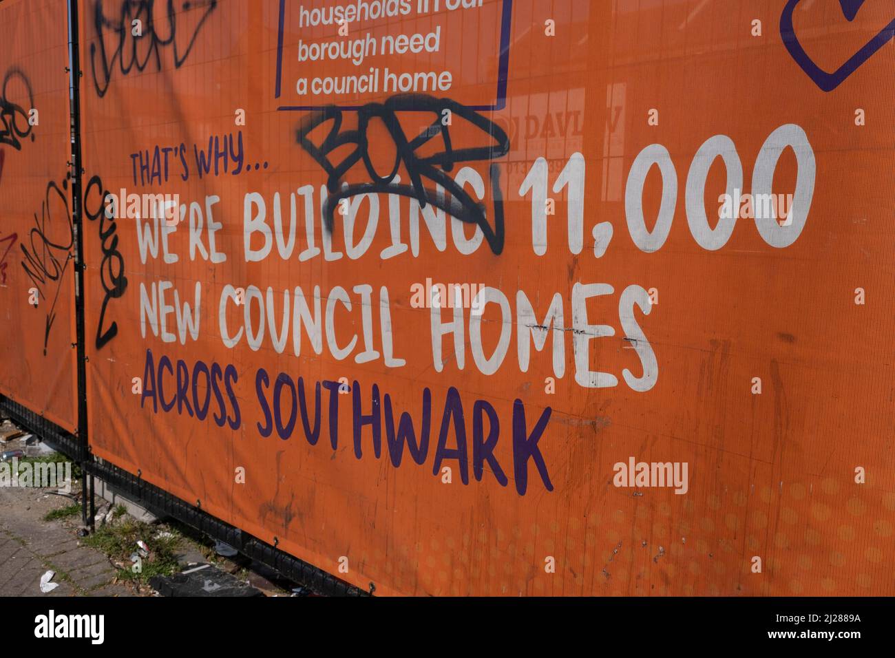 Hoarding advertising the fact that the local council are building 11,000 new council homes near the Old Kent Road on 24th March 2022 in London, United Kingdom. Old Kent Road is a major thoroughfare in South East London passing through the Borough of Southwark. It was originally part of an ancient trackway that was paved by the Romans. It is now part of the A2, a major road from London to the South East coast. Nowadays the surroundings have a run down feel, and while there are many new housing developments, it has a very strong old East End atmosphere, with the more modern twist of a very multi Stock Photo