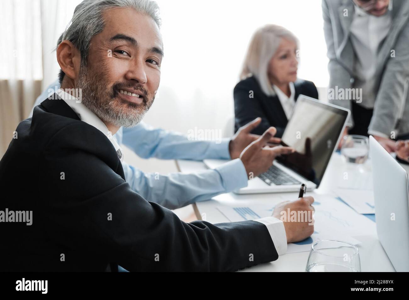 Business senior Asian man smiling at camera while working inside bank
