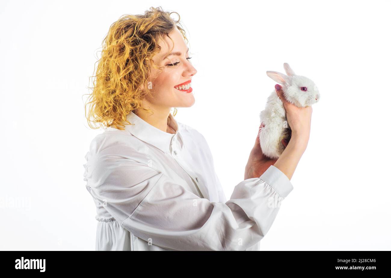 Happy woman with white baby rabbit. Smiling Girl with little Easter bunny. Cute furry hare. Stock Photo
