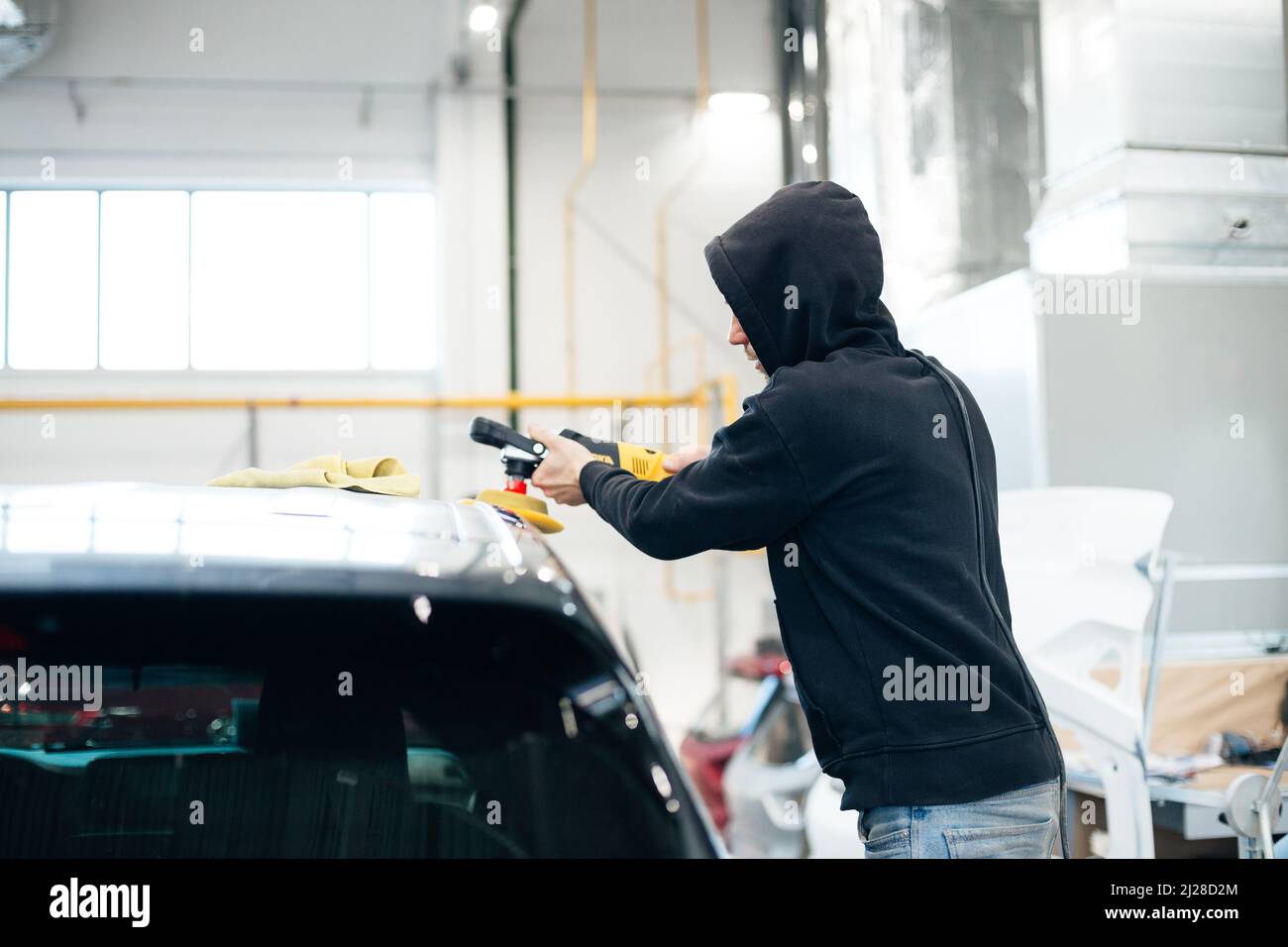 professional mechanic using a polisher for cleaning a car from scratches. Stock Photo