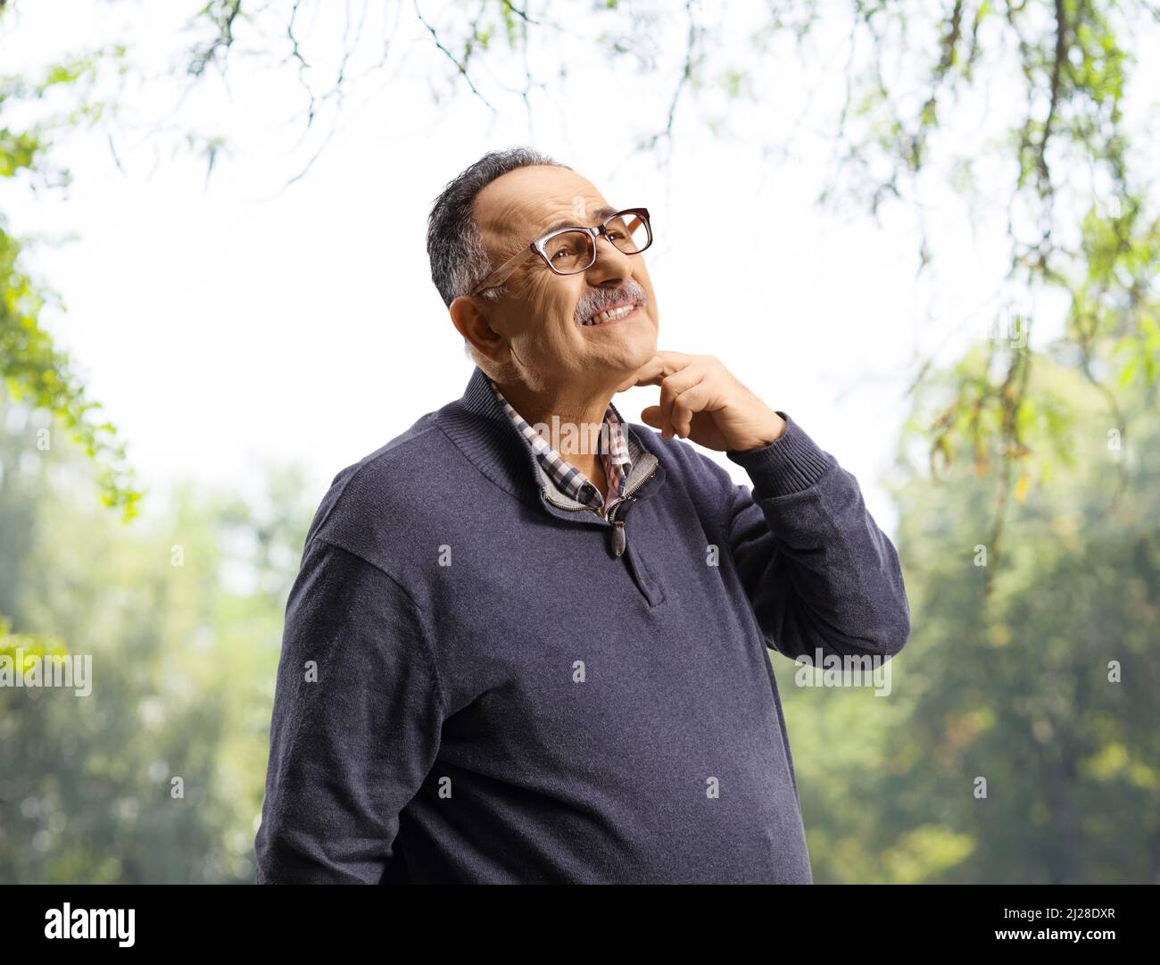 Mature man itching his neck outdoors in a park Stock Photo