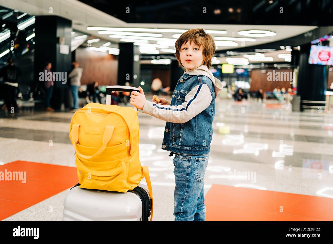 Child boy with backpack standing in the airport terminal, waiting for flight, travel with suitcase. Vacation concept Stock Photo