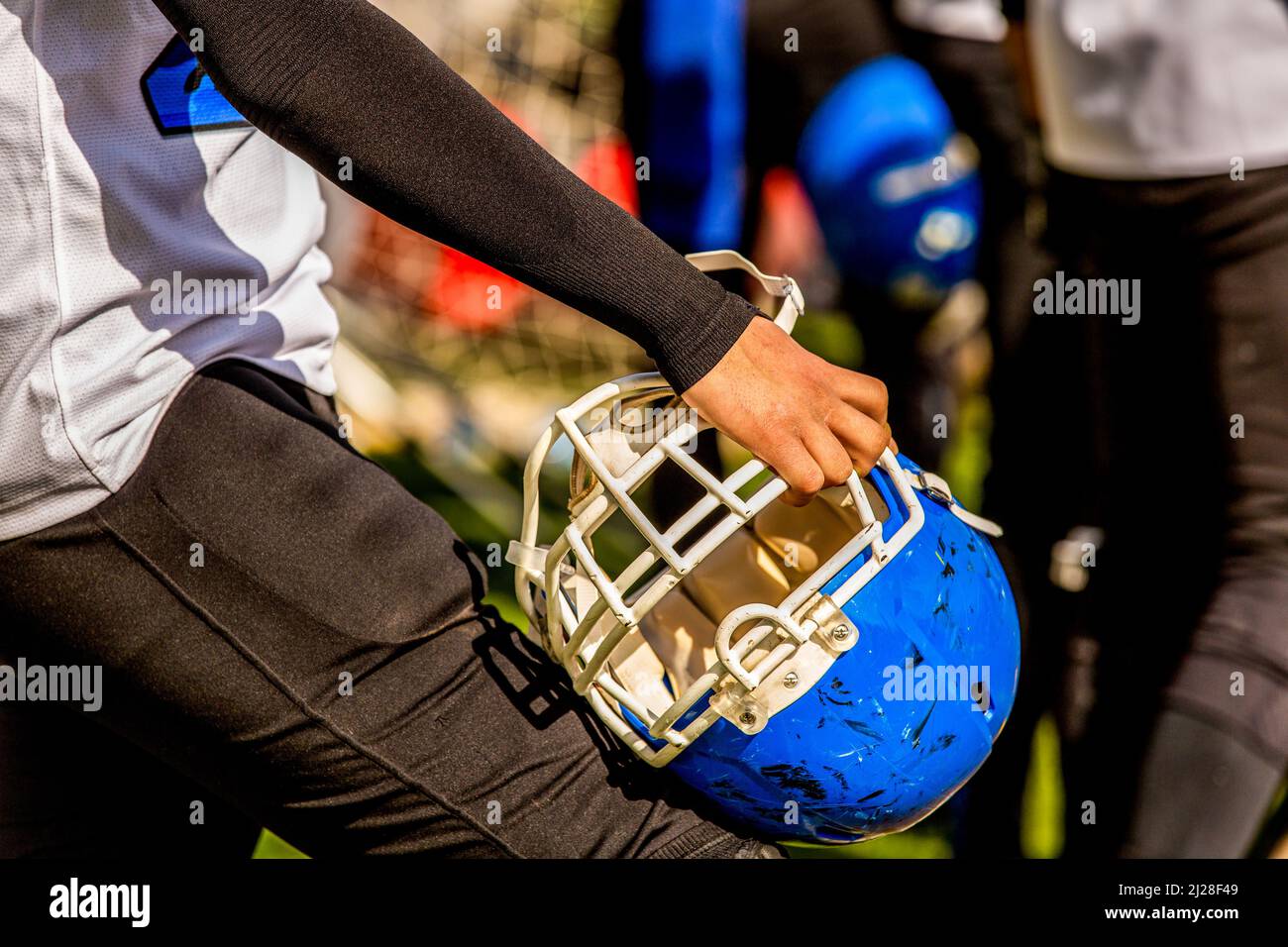 American football player holding protective helmet while waiting Stock Photo