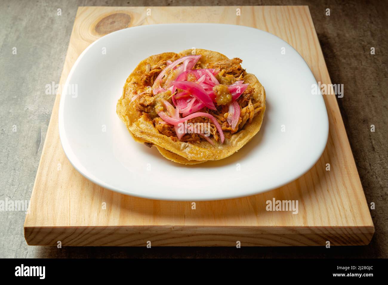 Cochinita Panuchos, gourmet Yucatecan food, meat with red onion and spicy red sauce, on a wooden background. Stock Photo