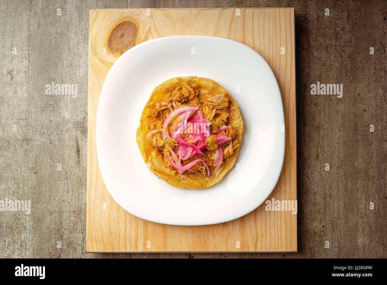 Cochinita Panuchos, gourmet Yucatecan food, meat with red onion and spicy red sauce, on a wooden background. Stock Photo