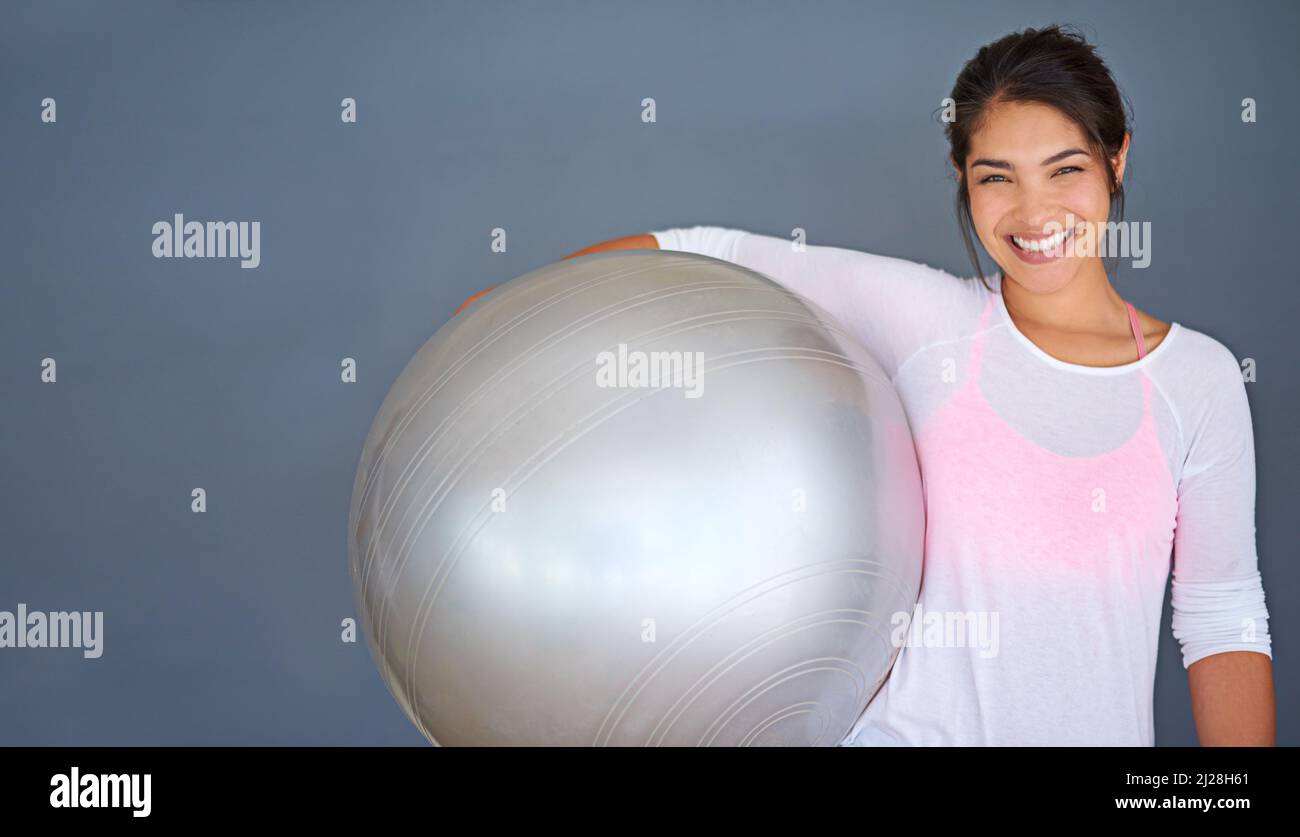 Improve your balance. Cropped shot of a sporty young woman holding a pilates ball against a grey background. Stock Photo
