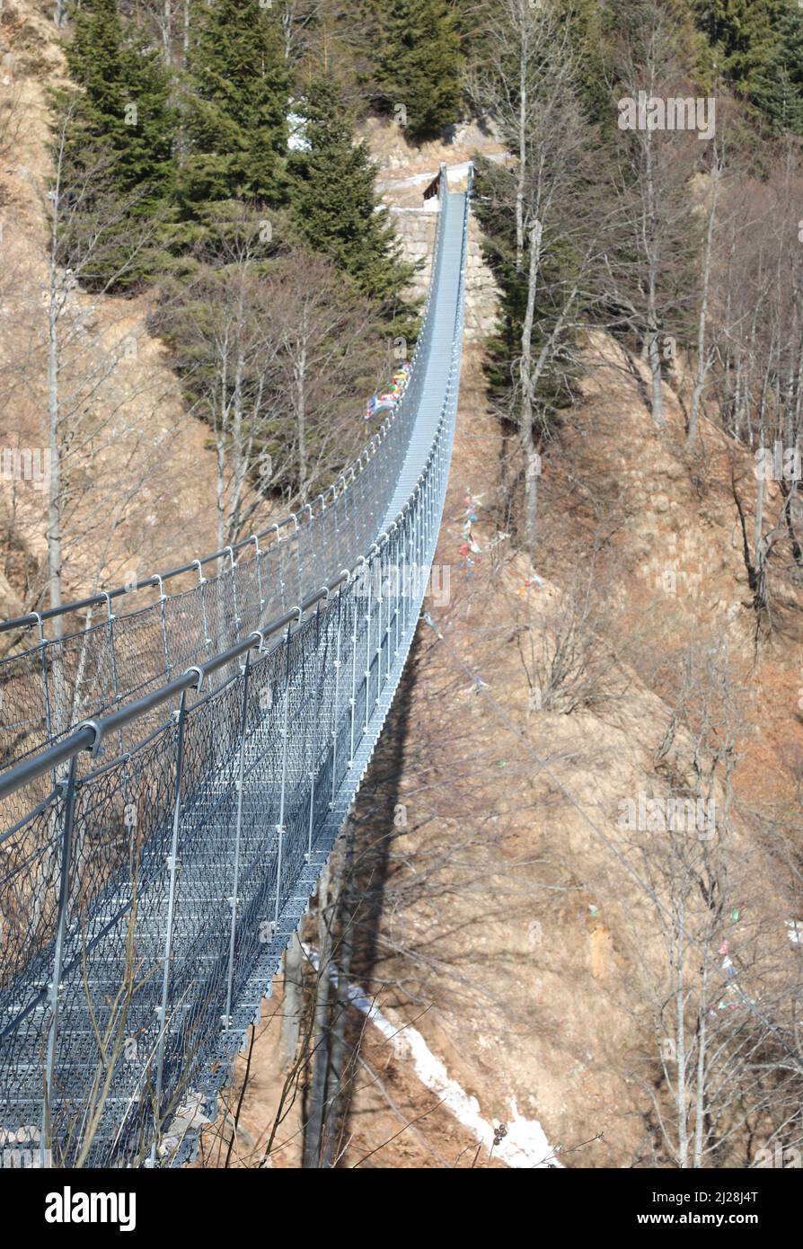 very long suspension bridge in stainless steel without people in winter in Northern Italy Stock Photo