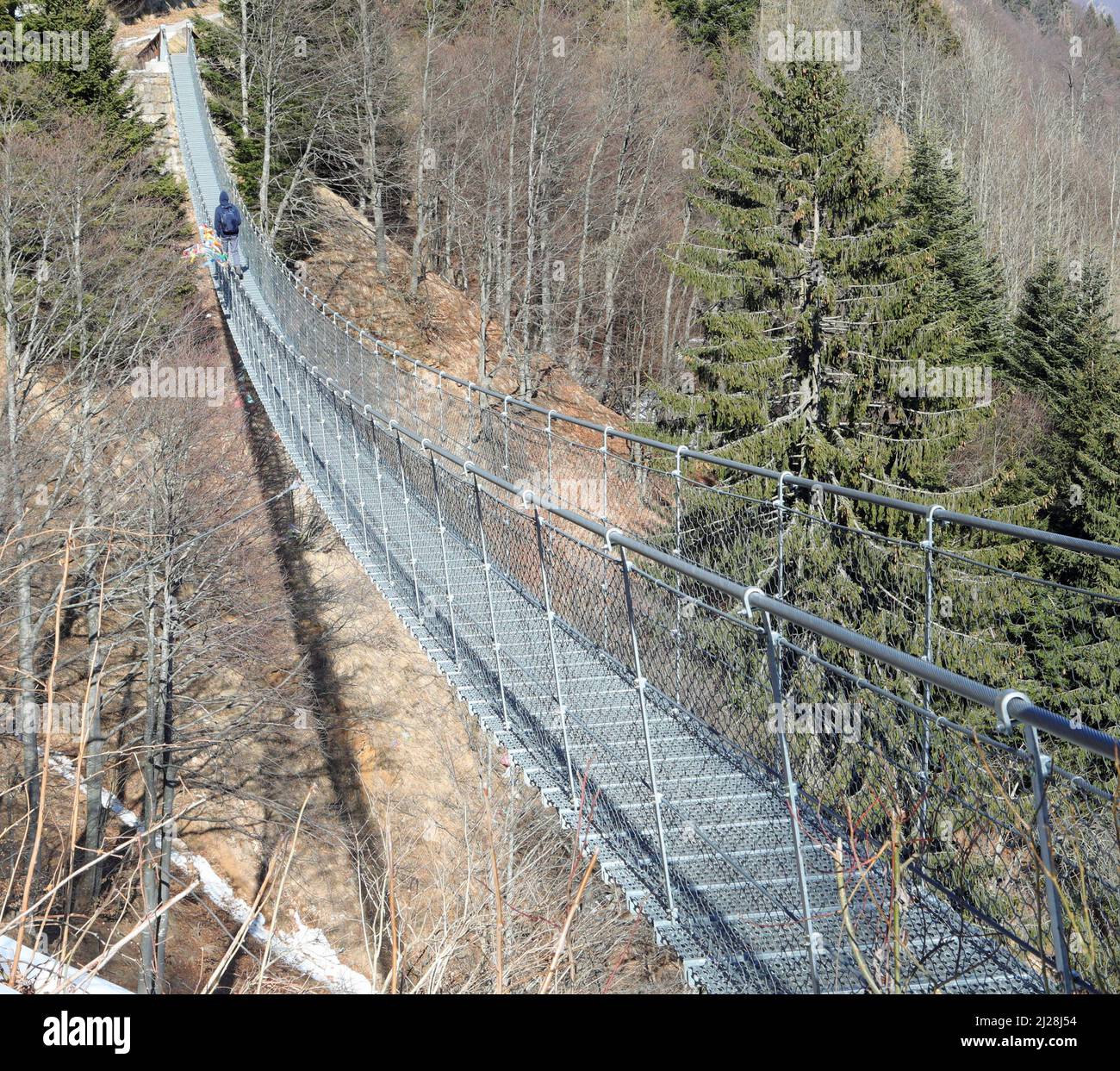 very long suspension bridge called Tibetan bridge and a person walking in winter Stock Photo