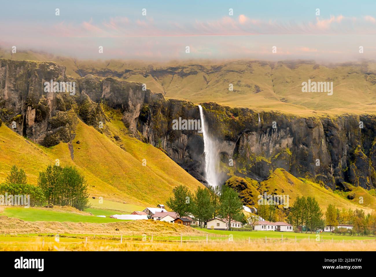 Small village near volcanic lava hills and a waterfall in Southern