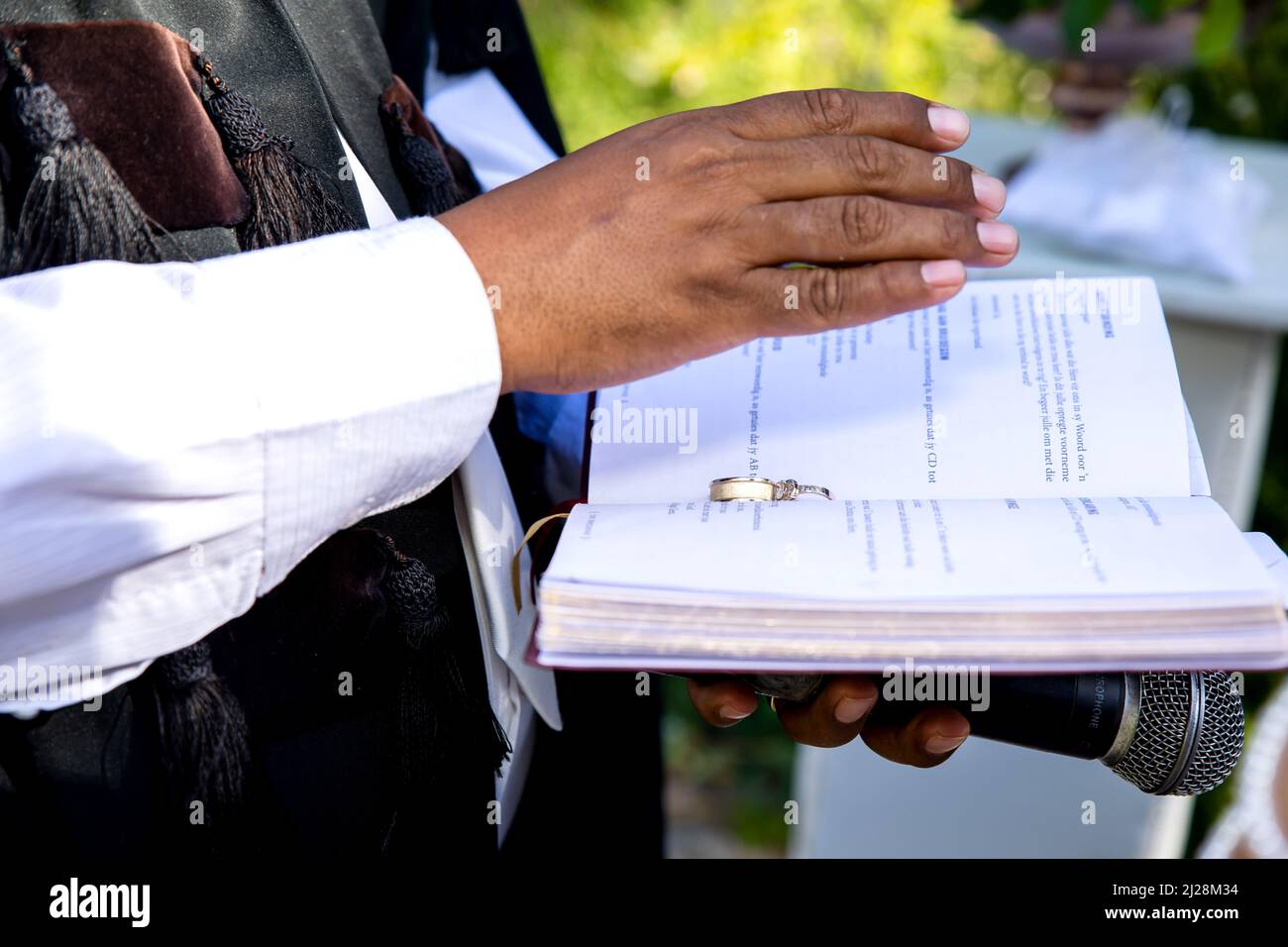 Preacher's hand over wedding bands on Bible Stock Photo Alamy