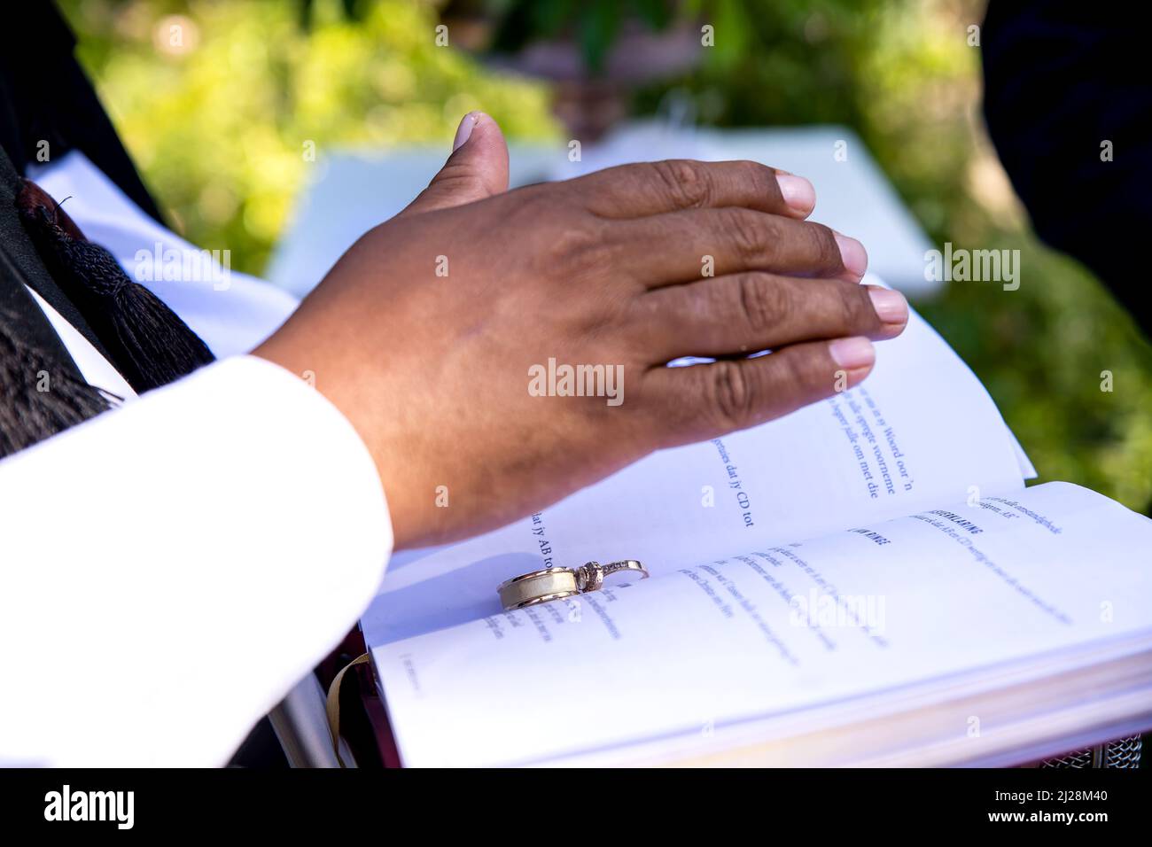 Preacher's hand over wedding bands on Bible Stock Photo Alamy