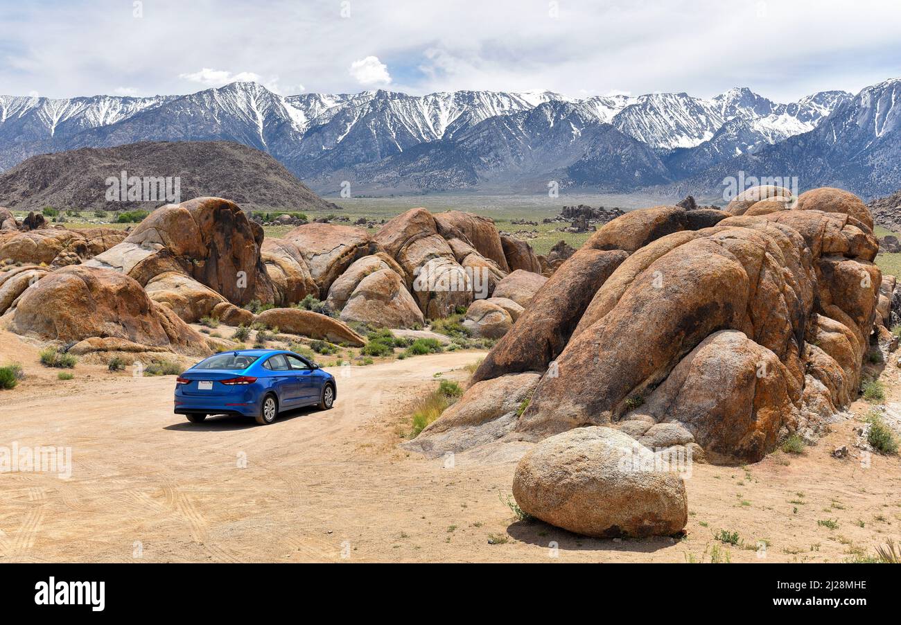 Blue car from California crossing the desert landscape of Alabama Hills (Lone Pine). Stock Photo