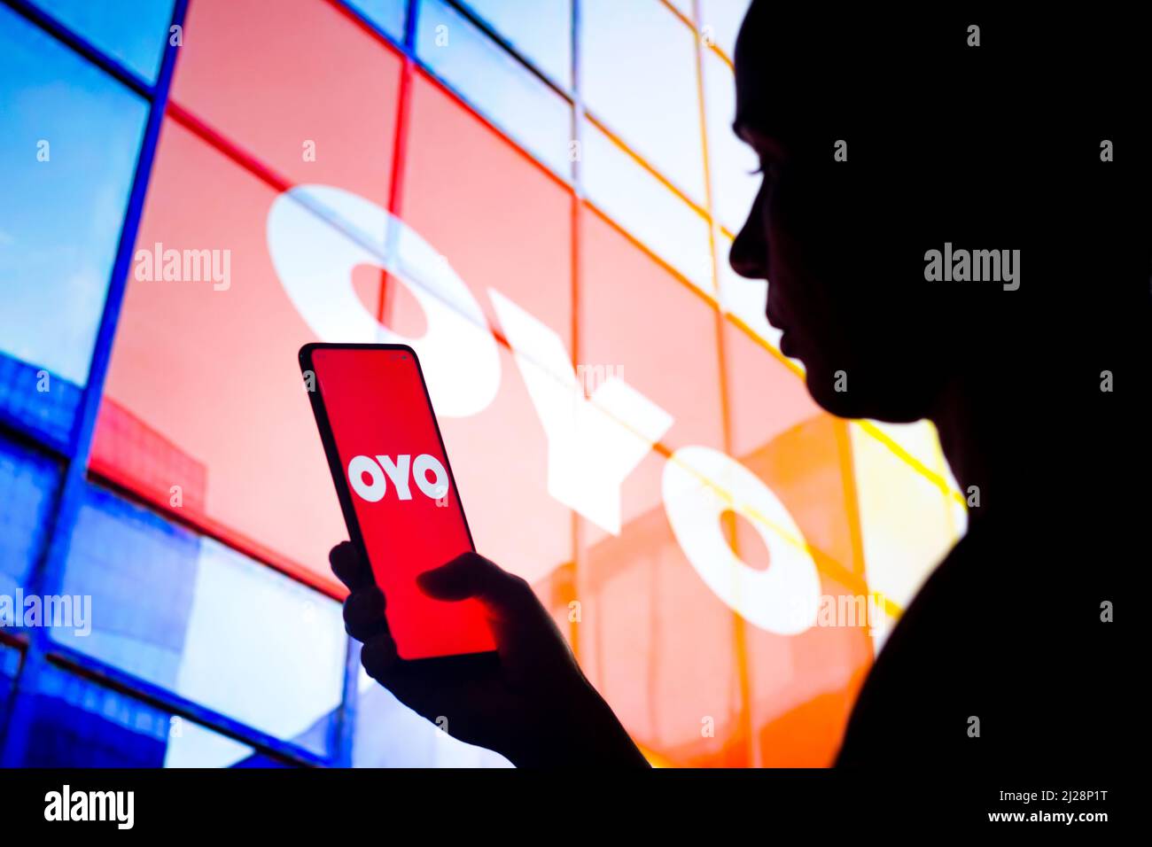 Brazil. 30th Mar, 2022. In this photo illustration, a woman's silhouette  holds a smartphone with the OYO Rooms logo displayed on the screen and in  the background. Credit: SOPA Images Limited/Alamy Live
