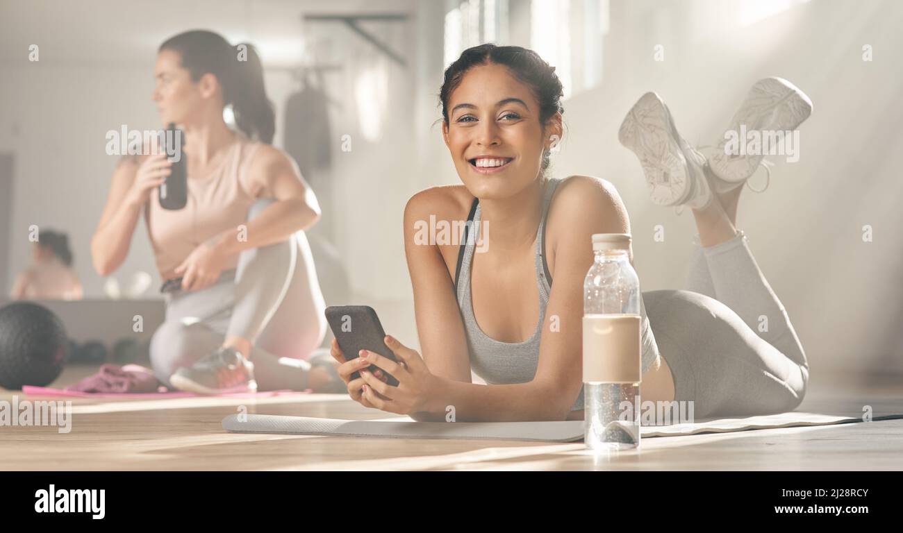 My virtual personal trainer gives me all the help I need. Shot of two young female athletes taking a break while at the gym. Stock Photo