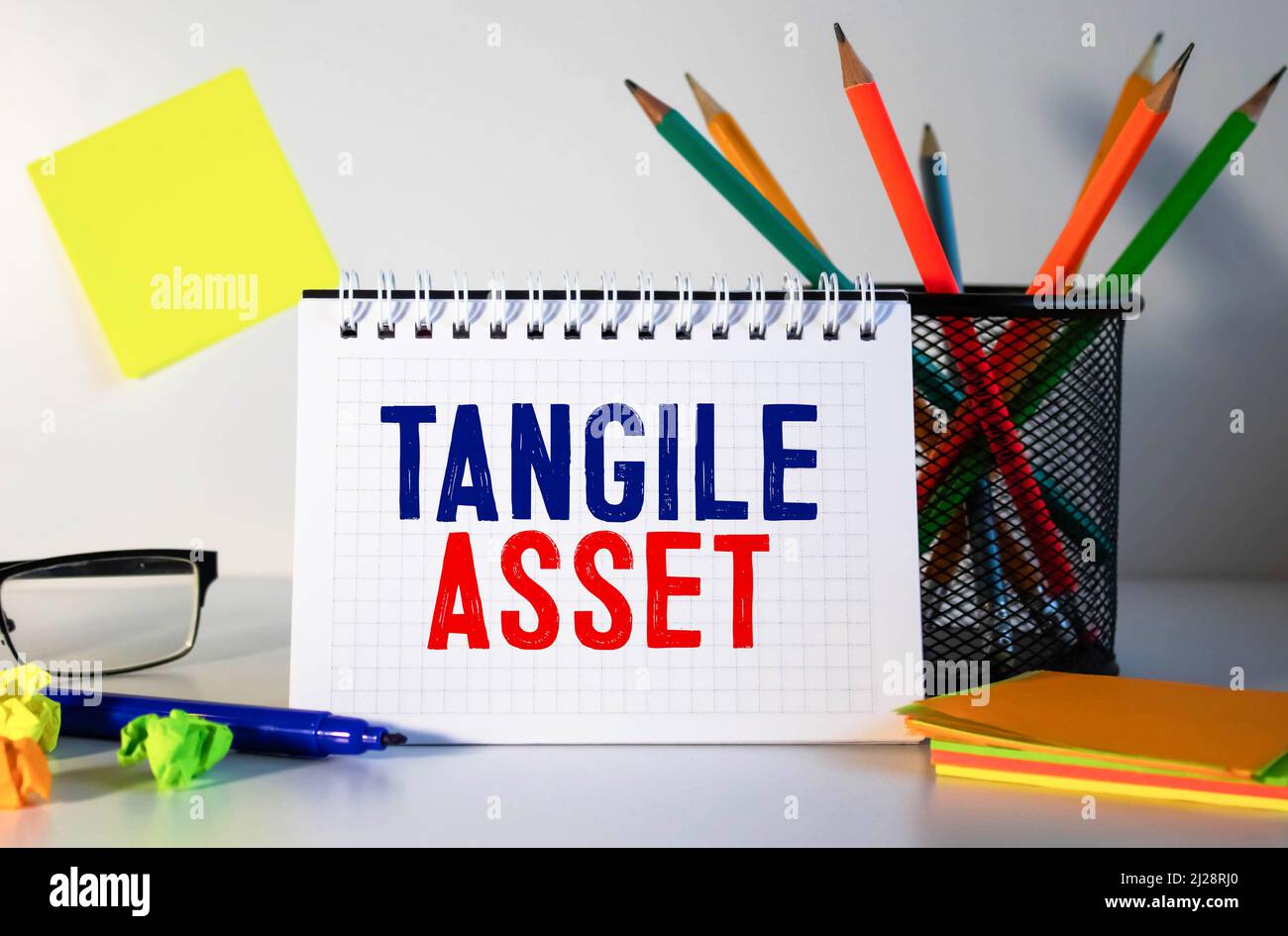 Tangible Asset text written on a notebook with pencils. Stock Photo