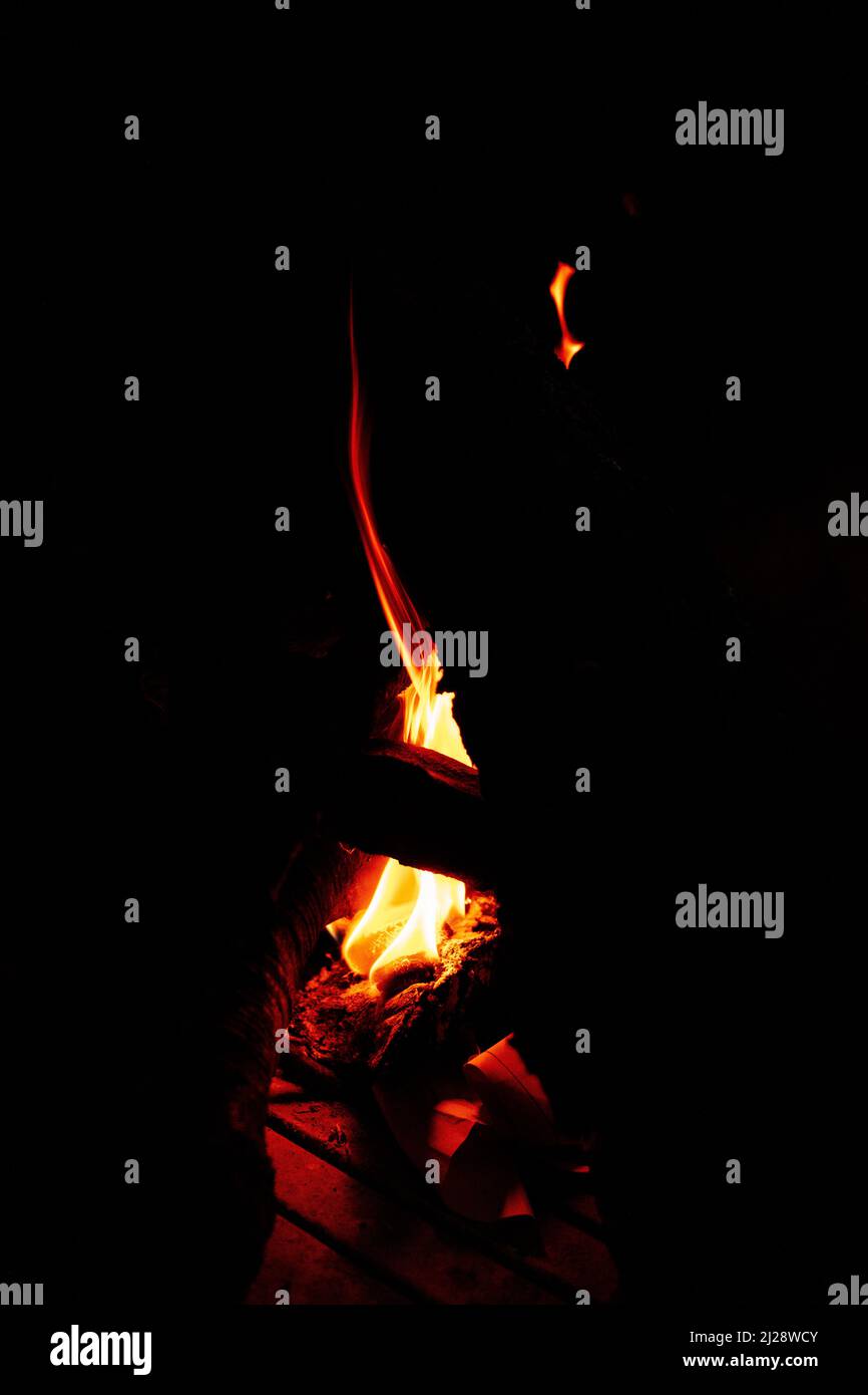 A faint flame of fire illuminates the darkness that surrounds her