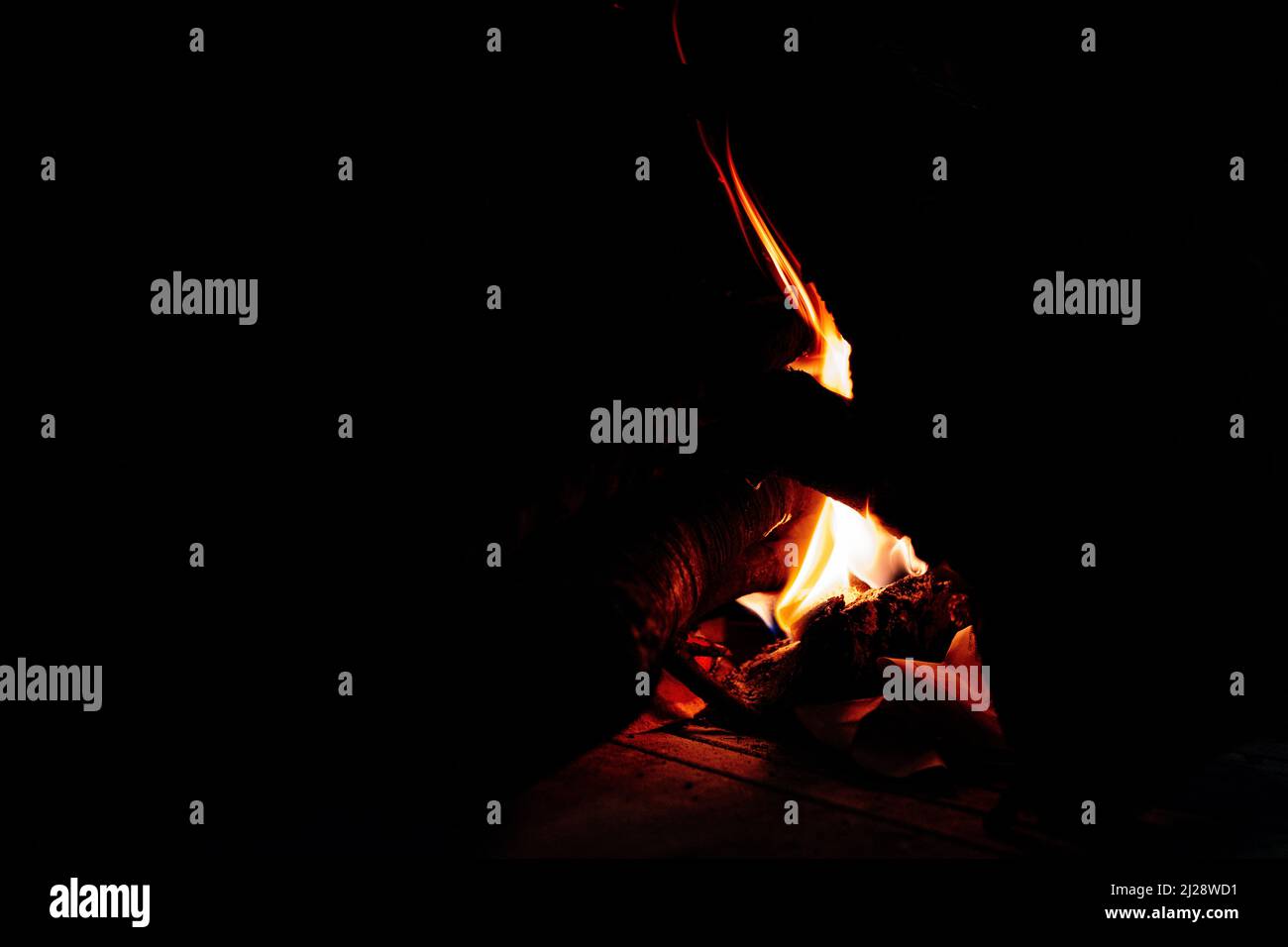 A faint flame of fire illuminates the darkness that surrounds her