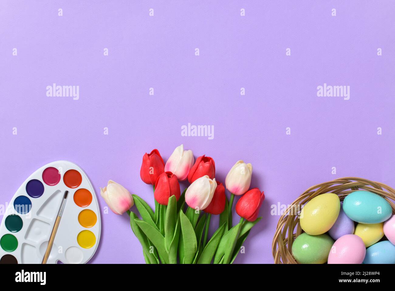 Easter background with painted eggs, paints and tulips. Copy space. Stock Photo