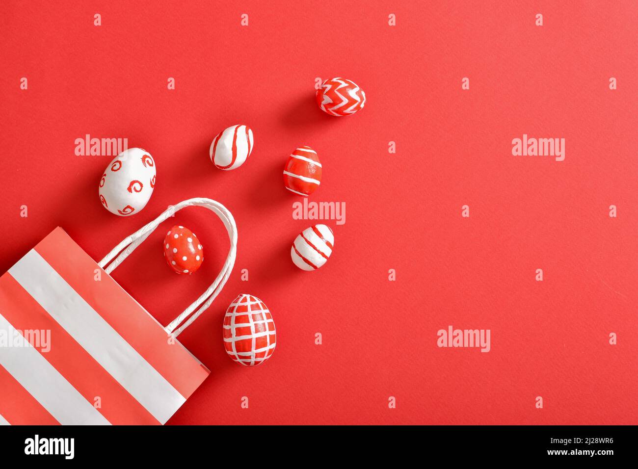 Paper eco-bag with painted Easter eggs on a red background. Stock Photo