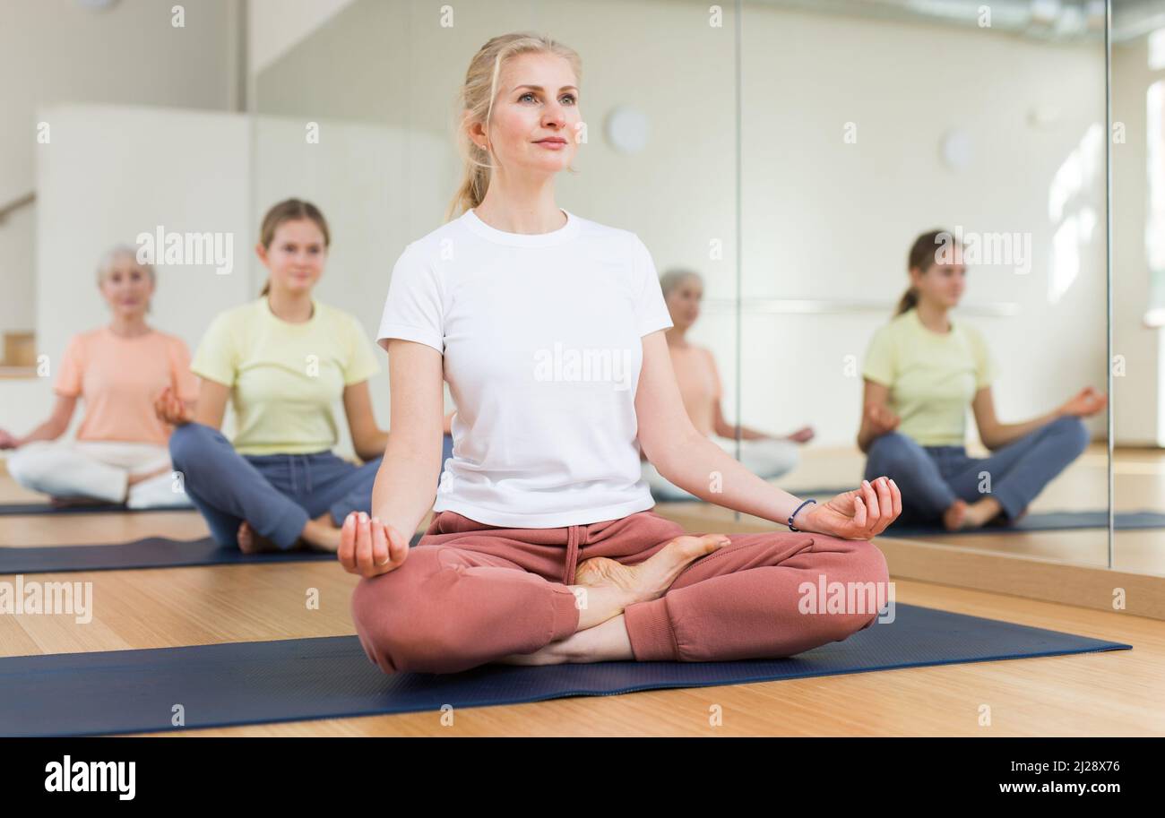 Continuity of generations - family in lotus position doing yoga in gym ...