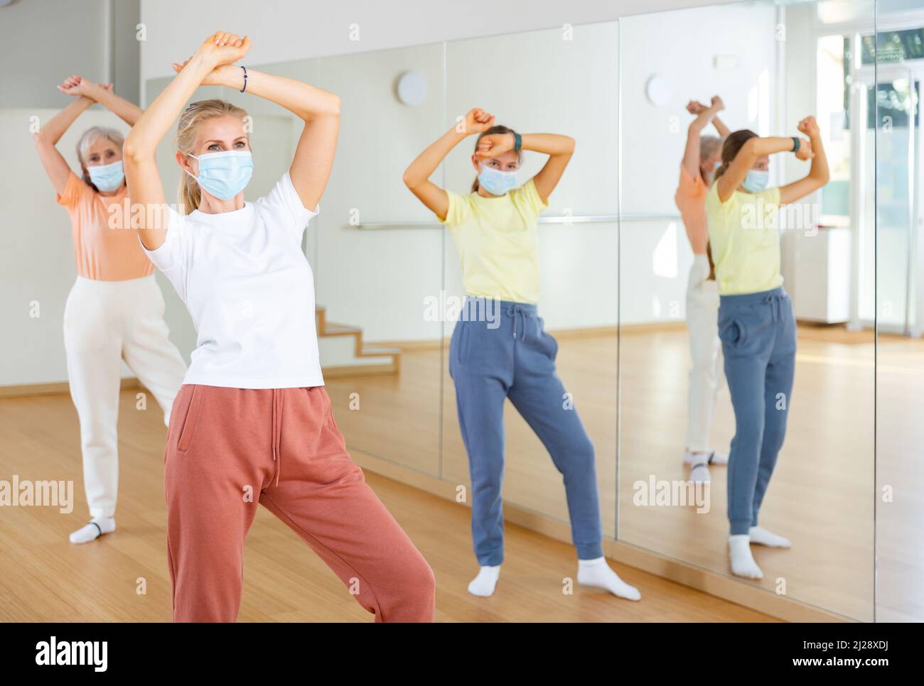 Woman in mask learning aerobic dance with her family in studio Stock ...