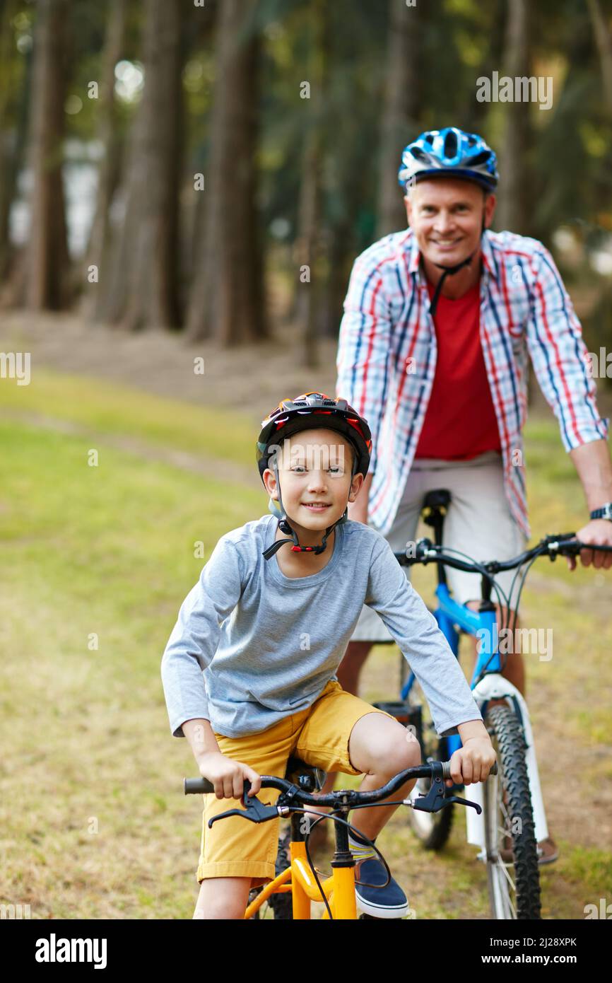 Lets ride. Portrait of a father and son riding bicycles in a park
