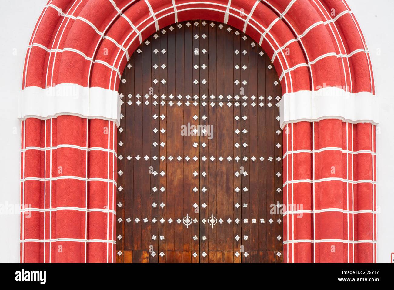 Arched wooden door with decorated white elements. Red style gate frame Stock Photo