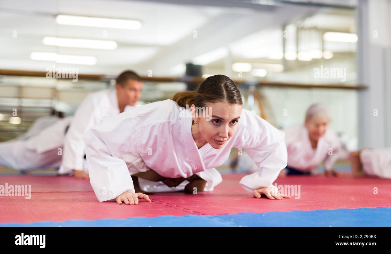 Young woman in kimono doing push-ups in gym Stock Photo