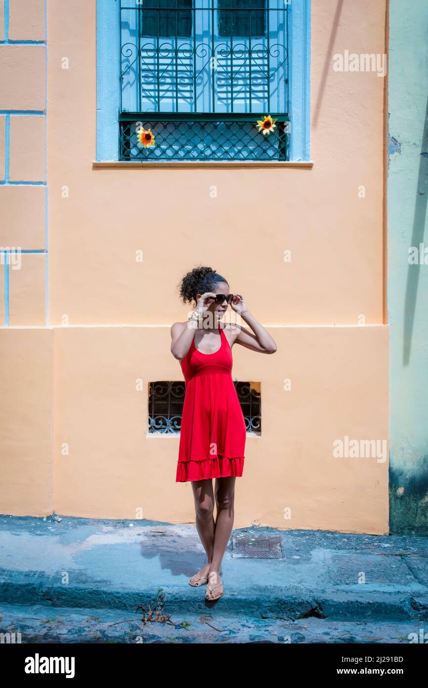 Portrait of a woman wearing red clothes on the street in bright sunny day. Salvador, Bahia, Brazil. Stock Photo