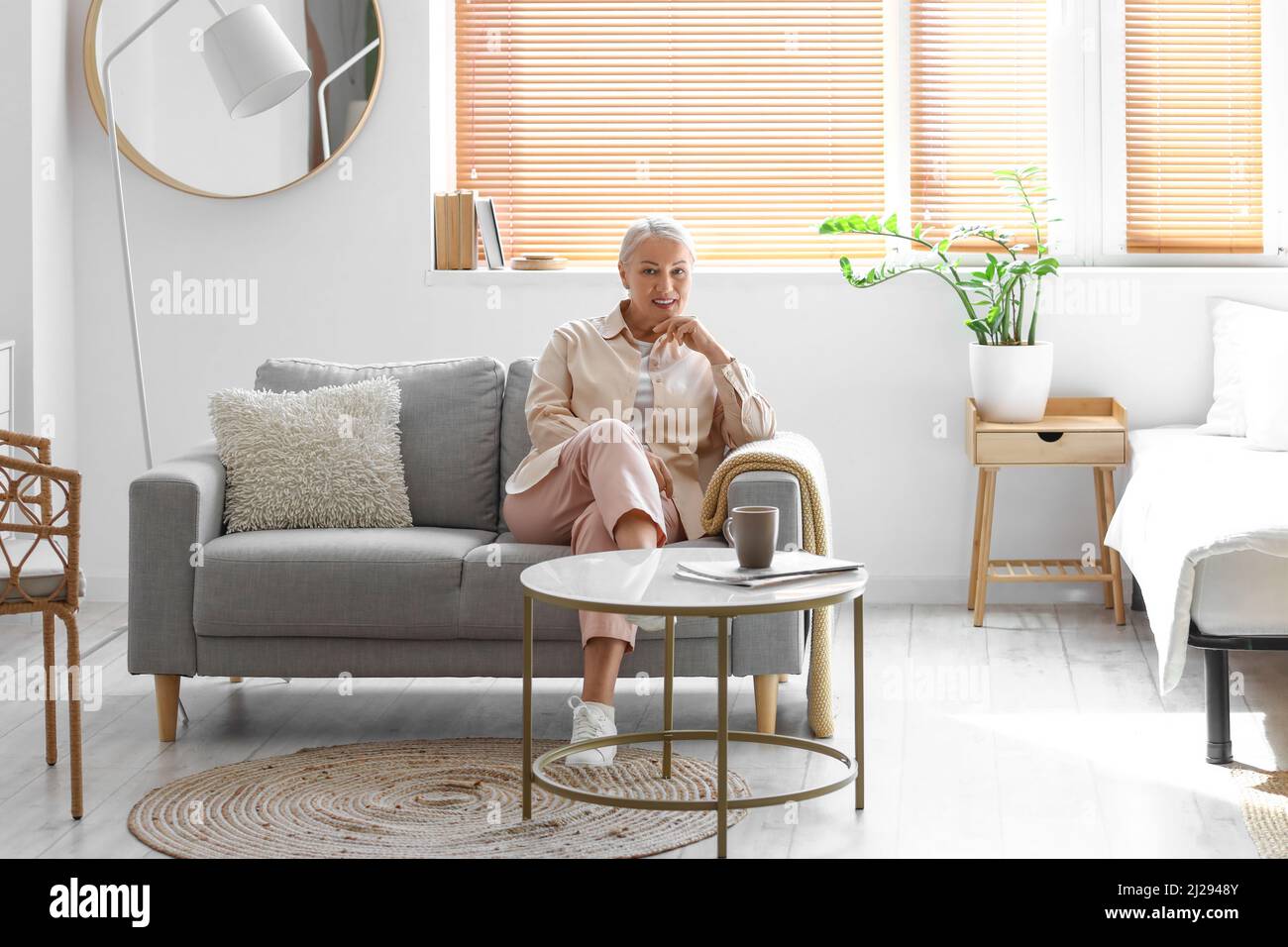 Mature woman sitting on soft sofa at home Stock Photo - Alamy