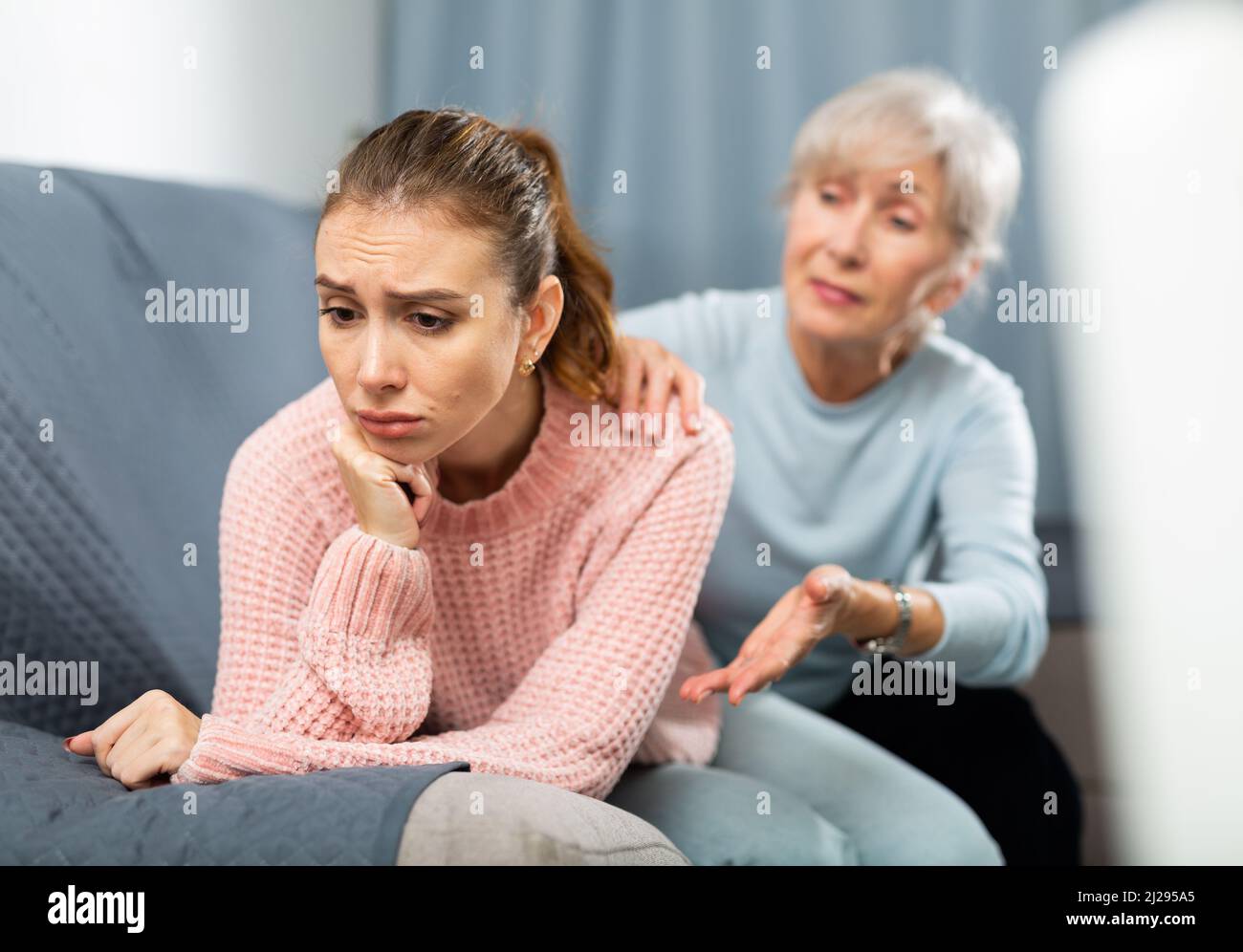 Senior woman calming chagrined adult daughter in home living room Stock ...