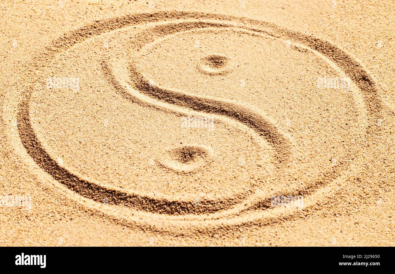 Balance is achievable. Shot of a yin and yang symbol drawn in sand ...