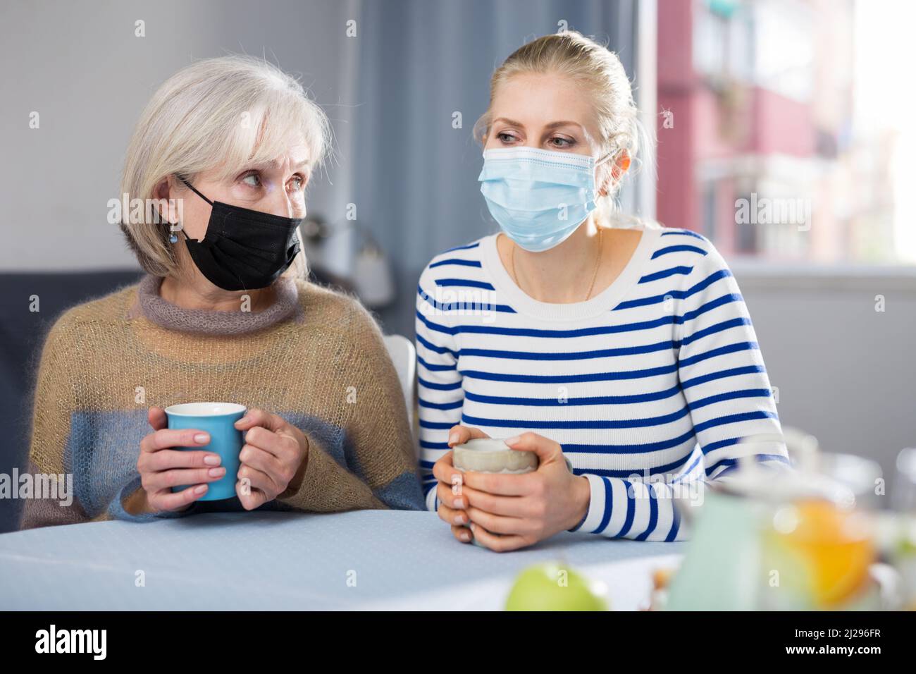 Two women in protective mask drink tea Stock Photo