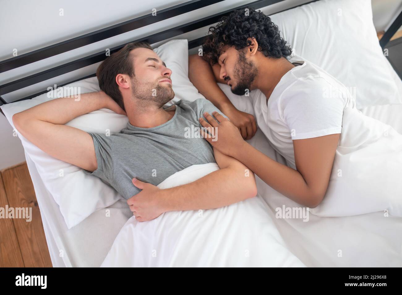 Young gay couple lying in bed during the sleep Stock Photo