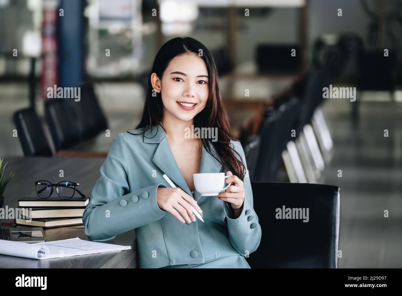 Young economist or accountant or financier and investor is drinking coffee while reading budget documents to study the impact and risk assessment of Stock Photo