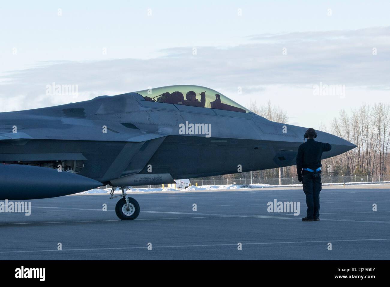 A U.S. Air Force Airman, a 525th Aircraft Maintenance Unit crew chief, marshals an F-22 Raptor during Polar Force 22-4 at Joint Base Elmendorf-Richardson, Alaska, March 30, 2022. The F-22 Raptor is celebrating its 25th anniversary on April 9 and was designed to project air dominance, provide an exponential leap in warfighting capabilities, and defeat threats against our nation’s Air Force, Army, Navy, and Marine Corps. U.S. forces will fly, sail, and operate anywhere international law allows, at the time and tempo of our choosing. (U.S. Air Force photo by Senior Airman Emily Farnsworth) Stock Photo