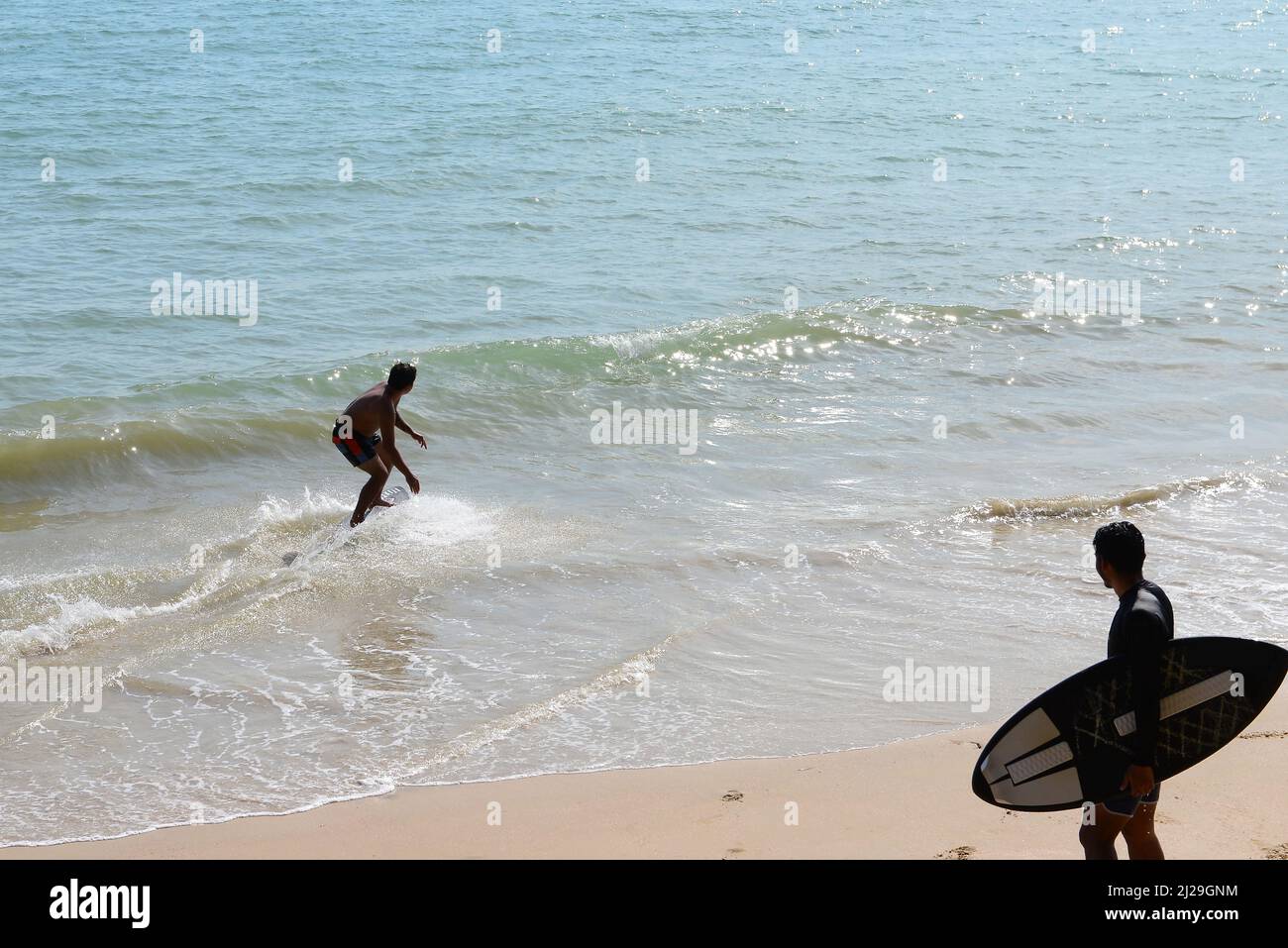 Two Man on a skimboard catching a wave in a beach in Aonang, Krabi ...