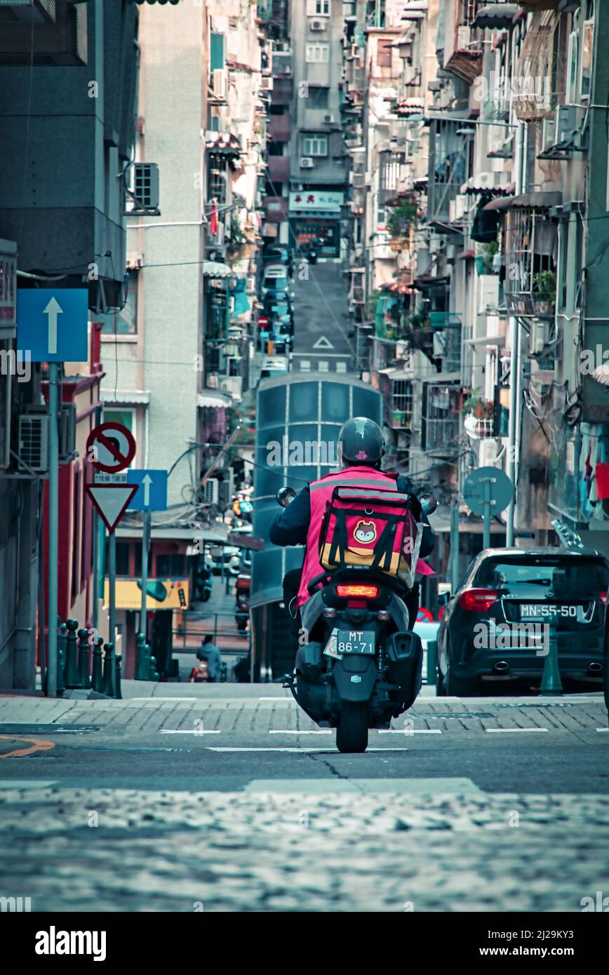 Adeliveryman on motorcycle on the street in Macau, China Stock Photo