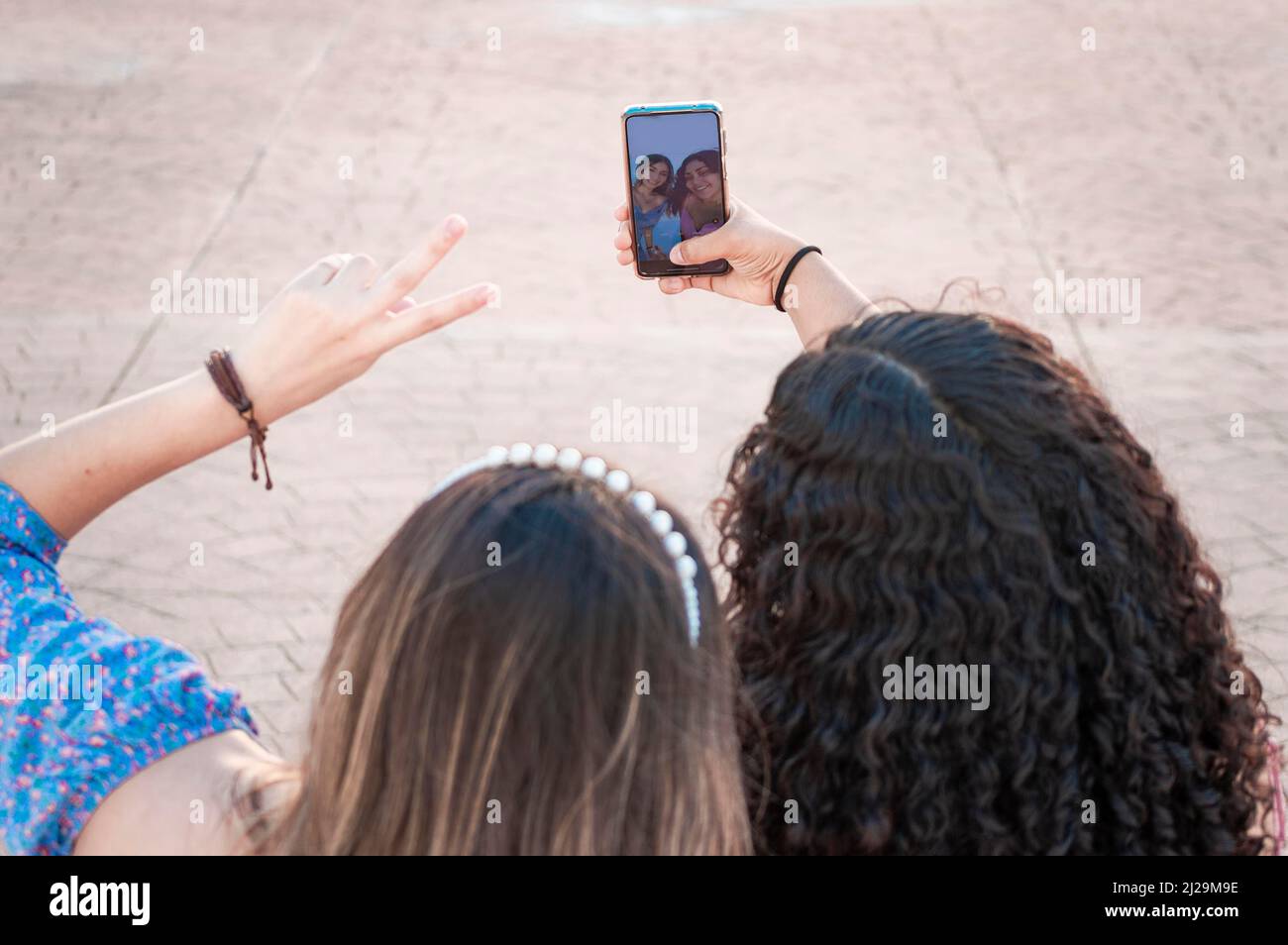 Two pretty girls taking a selfie, two latin girls smiling and taking a selfie, female friendship concept Stock Photo