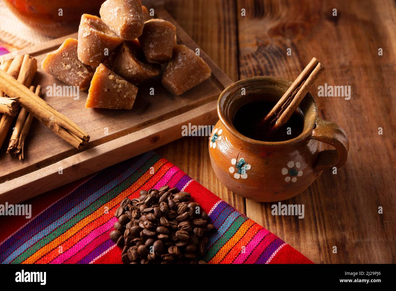 Cafe de Olla. Traditional Mexican coffee and basic ingredients for its preparation, coffee, cinnamon and piloncillo, served in a clay cup called 'jarr Stock Photo