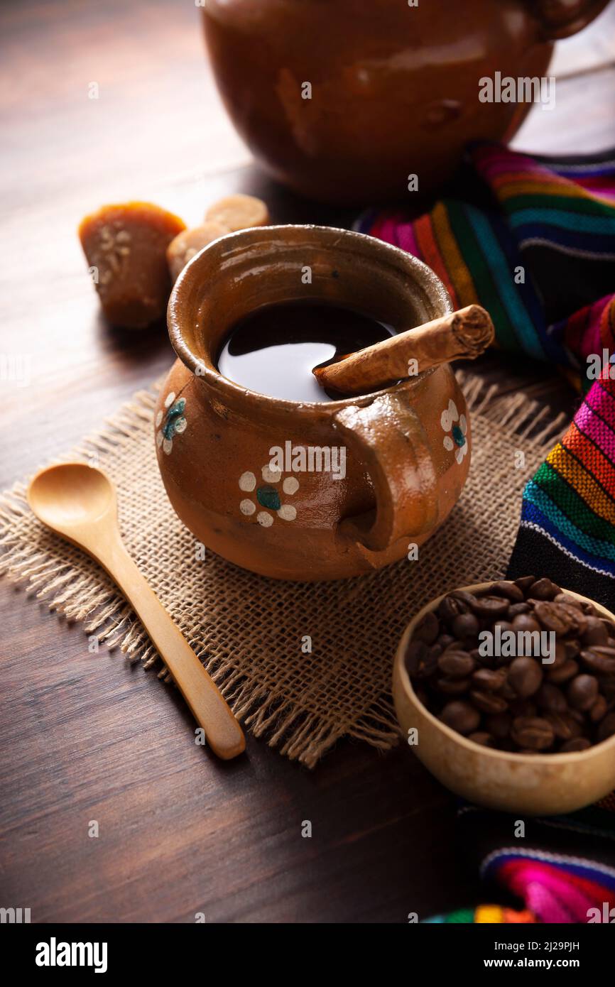 Cafe de Olla. Traditional Mexican coffee and basic ingredients for its preparation, coffee, cinnamon and piloncillo, served in a clay cup called 'jarr Stock Photo