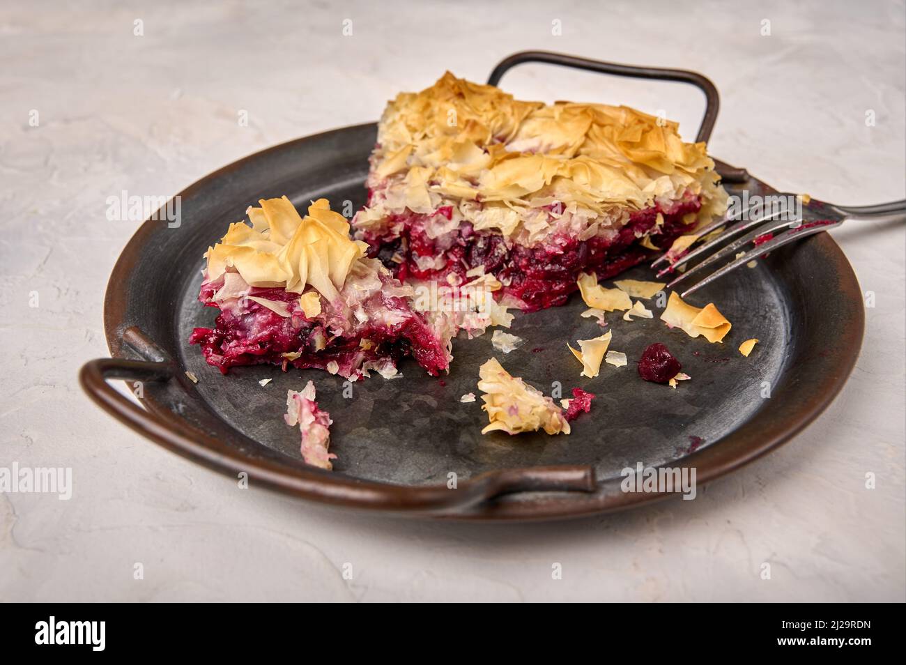 Pieces of cherry pie from filo dough and fork on rustic metal tray. Close up, selective focus Stock Photo