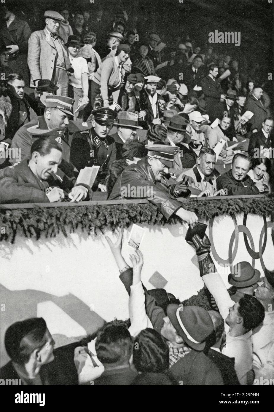 Reich Chancellor Adolf Hitler signs autographs for Canadian athletes in the Artificial Ice Stadium, with Reich Propaganda Minister Joseph Goebbels to Stock Photo