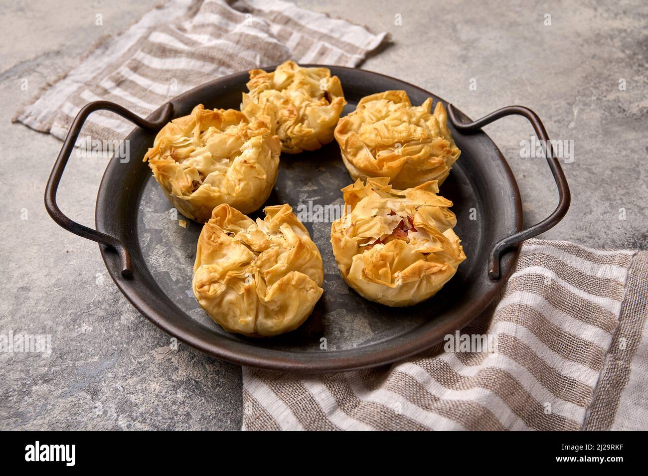 Cherry cakes from filo dough on metal tray with napkin on concrete background , close up Stock Photo