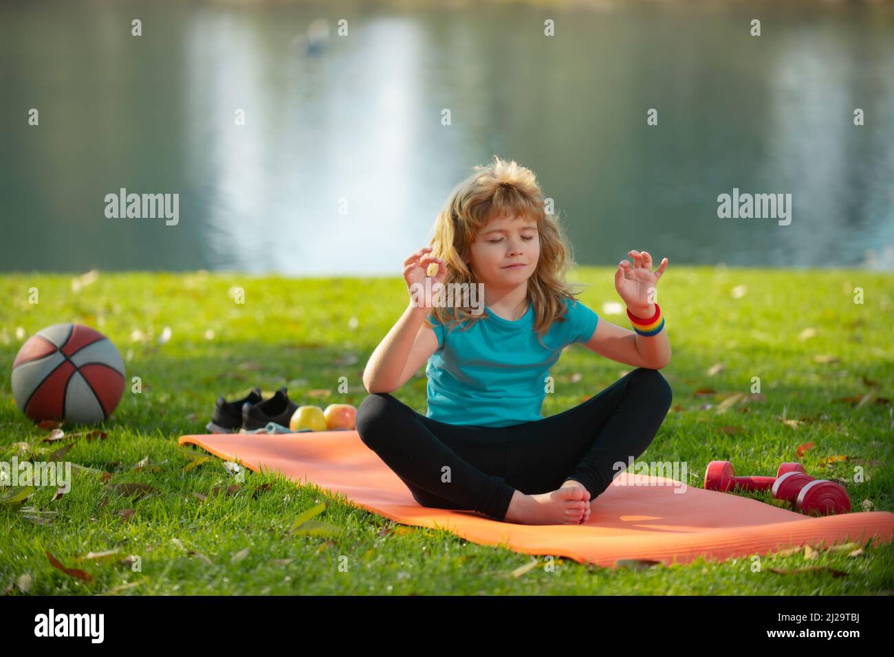 Kid doing meditate yoga asana on roll mat in park. Kids girl practicing ...
