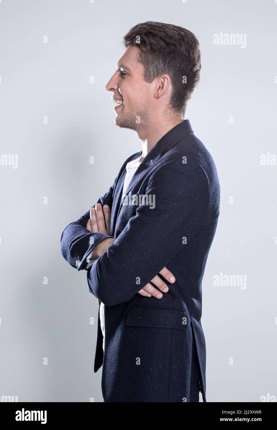 Portrait of a smart young man standing with arms crossed over gray ...