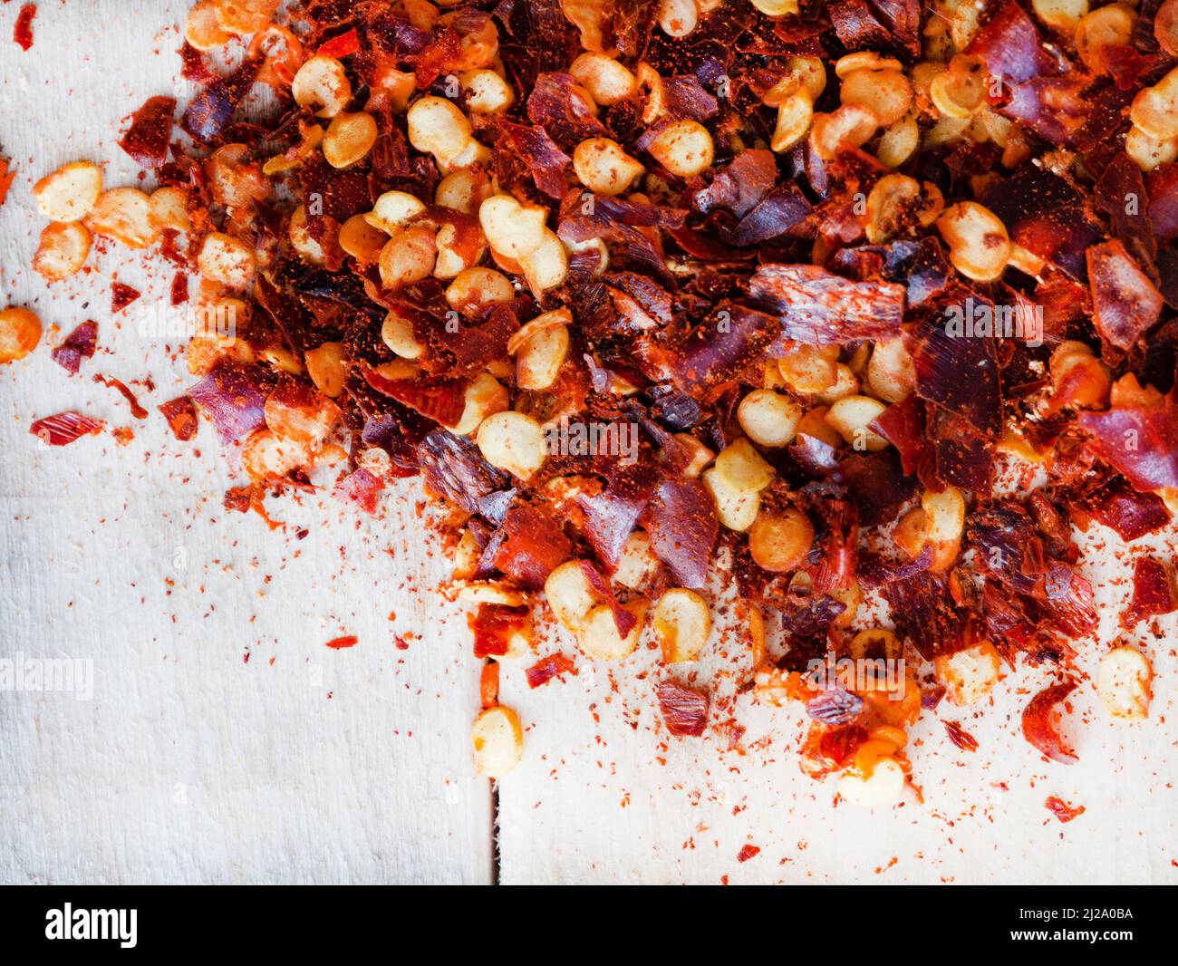 Dried red chili flakes on raw wooden surface Stock Photo